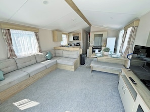 Ein gemütlicher Wohnbereich mit Sofa, Esstisch, Küchenzeile und Fernseher.