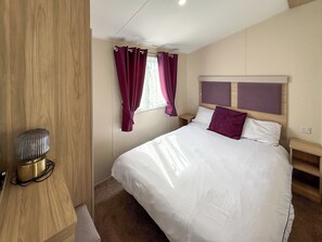 Ein Schlafzimmer mit Bett, Vorhängen, Nachttisch und Lampe.
