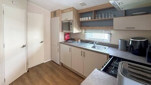 Cocina compacta con microondas, lavabo y estufa.