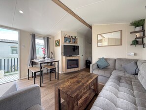 Ein modernes Wohnzimmer mit einer Couch, einem Couchtisch, einem Fernseher und einem Kamin.