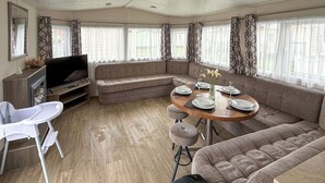 A modern RV interior with a dining area, seating, a TV, and a kitchenette. - Sunnymede D1 - UKC9574 (Ingoldmells)