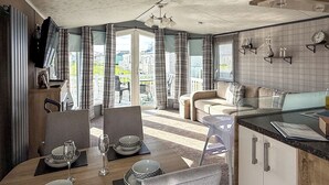 Een moderne keuken met een eethoek, grote ramen en uitzicht op buiten.