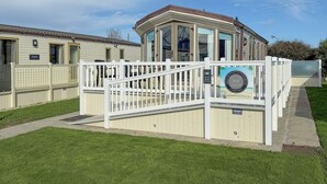 Een rij vakantiehuisjes met een witte hekken en een overdekt terras.