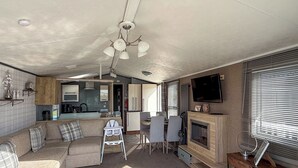 Een knus woongedeelte met een bank, eettafel, televisie, open haard en kitchenette.
