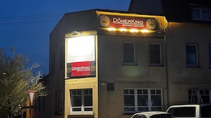 Ein Gebäude mit einem Schild, auf dem 'DÖNERKING EINFACH LECKER!' steht, und einem dreieckigen Verkehrsschild.