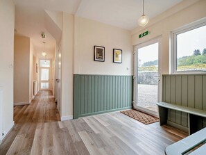 Ein Flur mit Holzboden, einer Bank, einer Tür mit Blick und zwei gerahmten Zitaten an der Wand.
