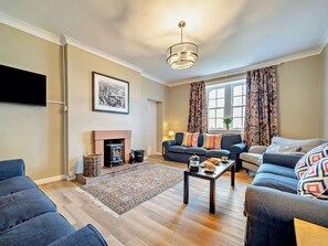 Ein Wohnzimmer mit Kamin, Sofa, Couchtisch und Fernseher.