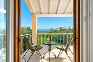 Ein Balkon mit zwei Stühlen und einem Tisch, Blick aufs Meer und klarer Himmel.