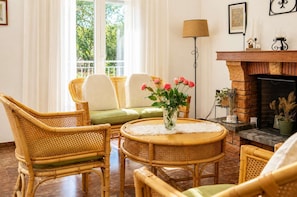 Ein Zimmer mit Korbmöbeln, einem Kamin und einer Blumenvase.
