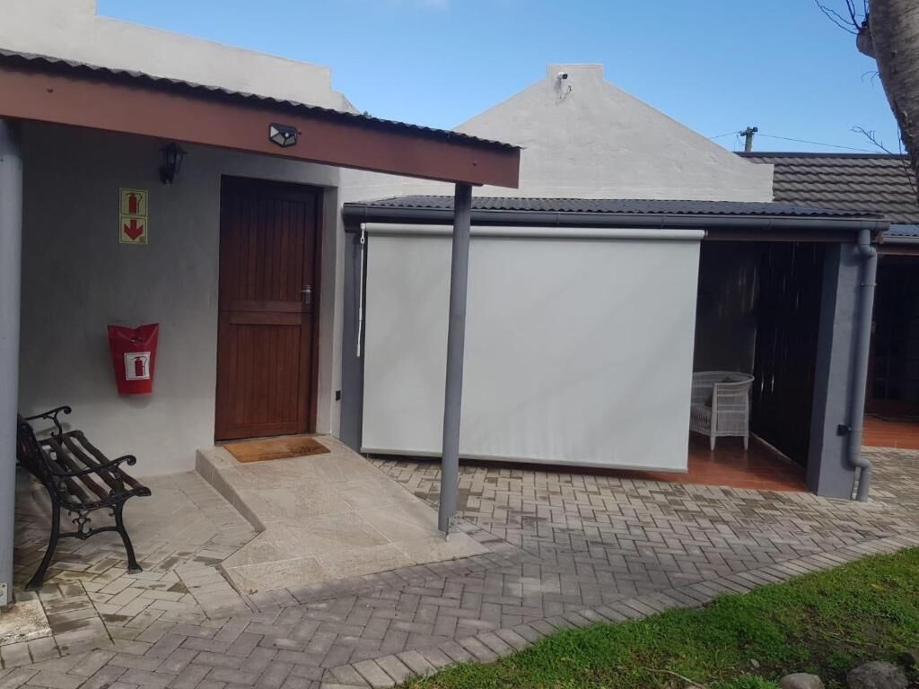 A building with a covered outdoor seating area, a door, and a bench.