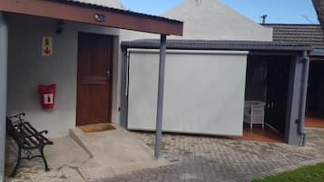 A building with a covered outdoor seating area, a door, and a bench.