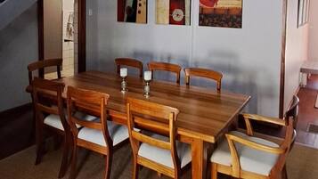 A dining area with a wooden table and chairs, a staircase, and artwork on the wall.