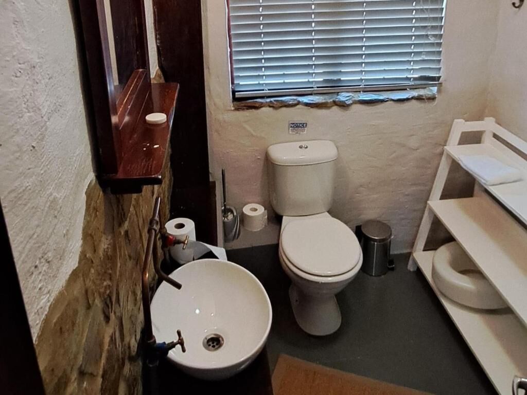 A small bathroom with a toilet, sink, and a notice on the wall.