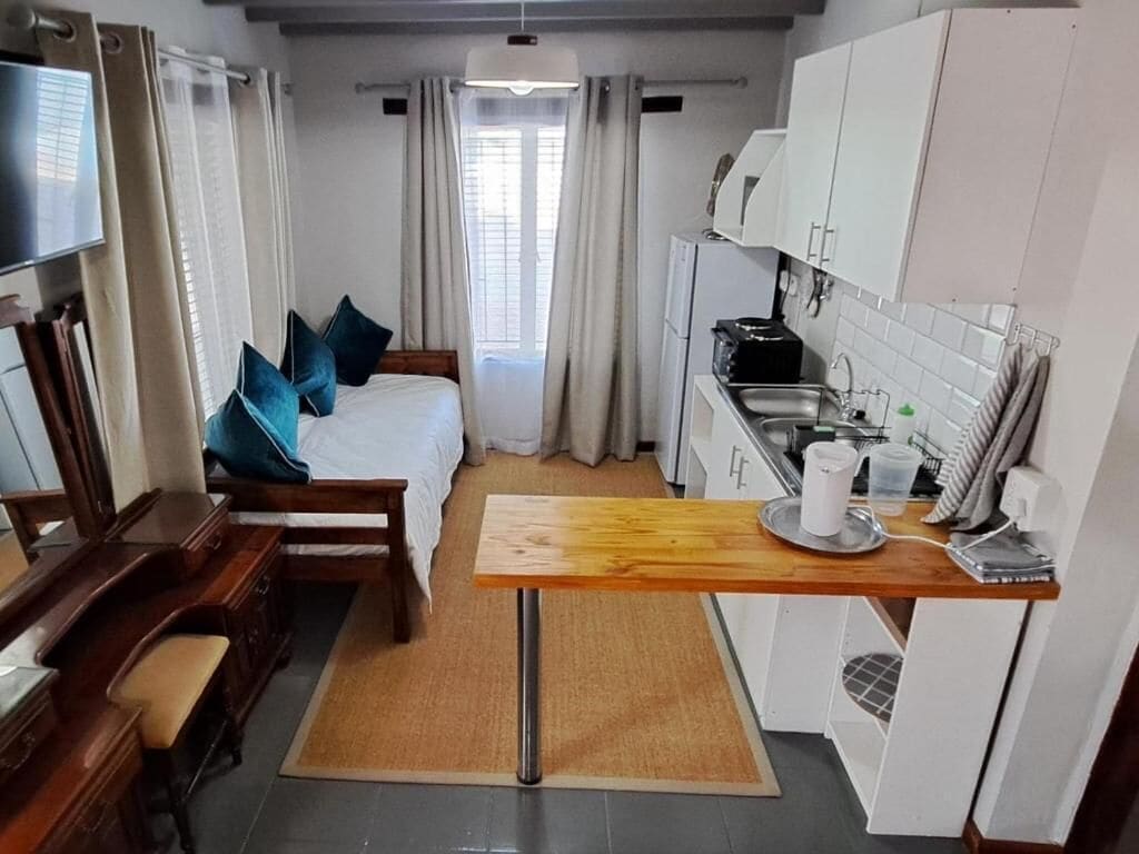 Een kleine hotelkamer met een bed, een bureau, een kitchenette en een televisie.