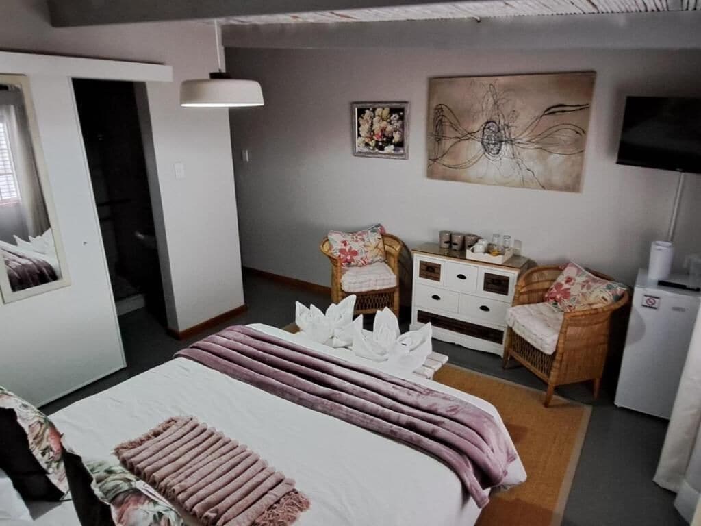 A hotel room with a bed, a desk, a chair, a television, and artwork on the wall.