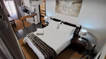 A hotel room with a bed, bedside tables, a desk, and a chair.