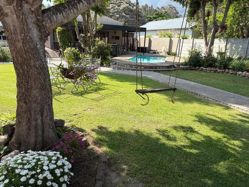 Un jardin avec une balançoire, une piscine et une pelouse.