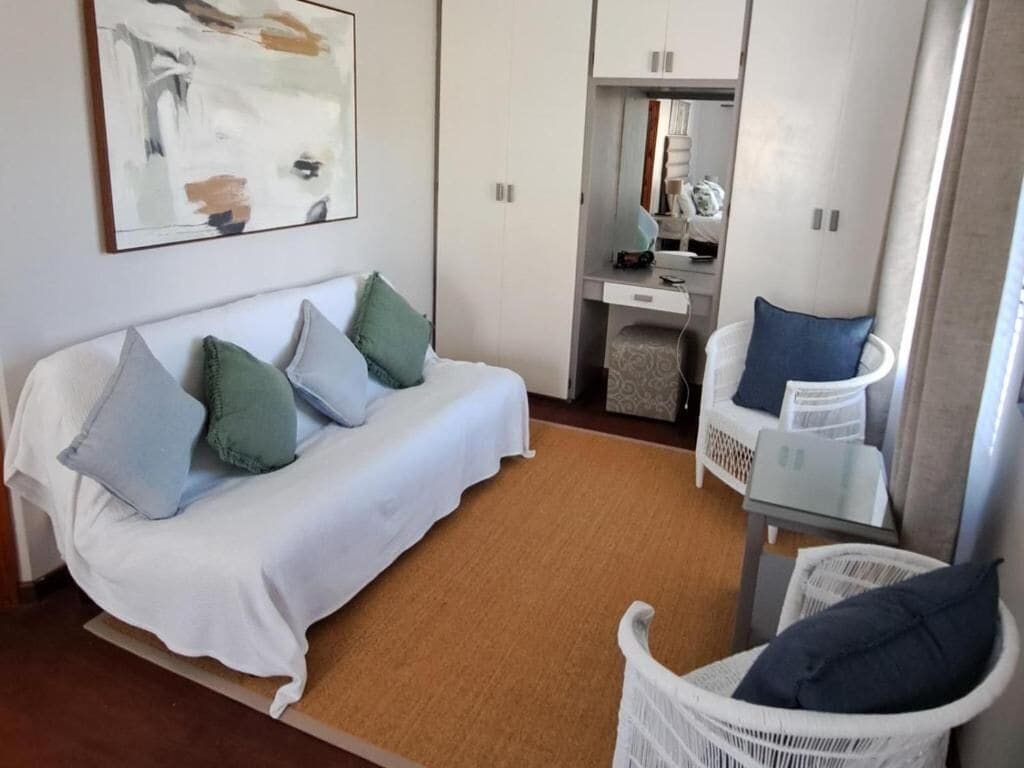 Une pièce de taille modeste, avec un canapé blanc, un petit bureau et une chaise.