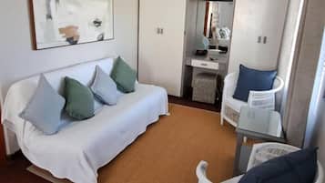 Une pièce de taille modeste, avec un canapé blanc, un petit bureau et une chaise.