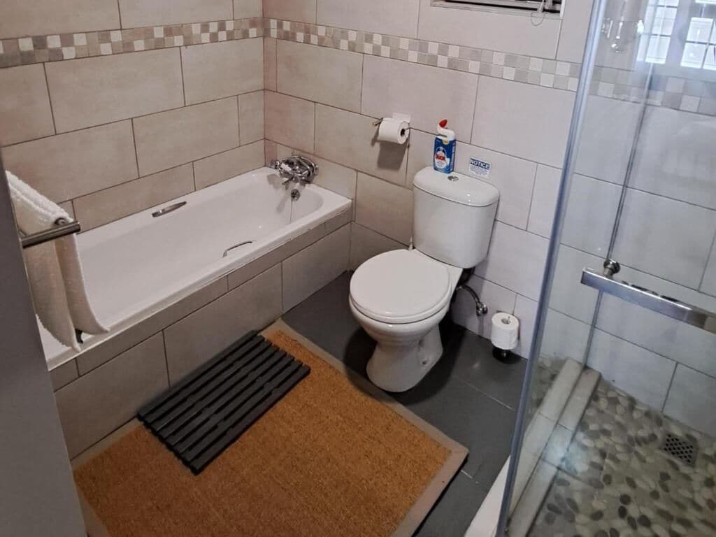 Et badeværelse med badekar, toilet og bruser.