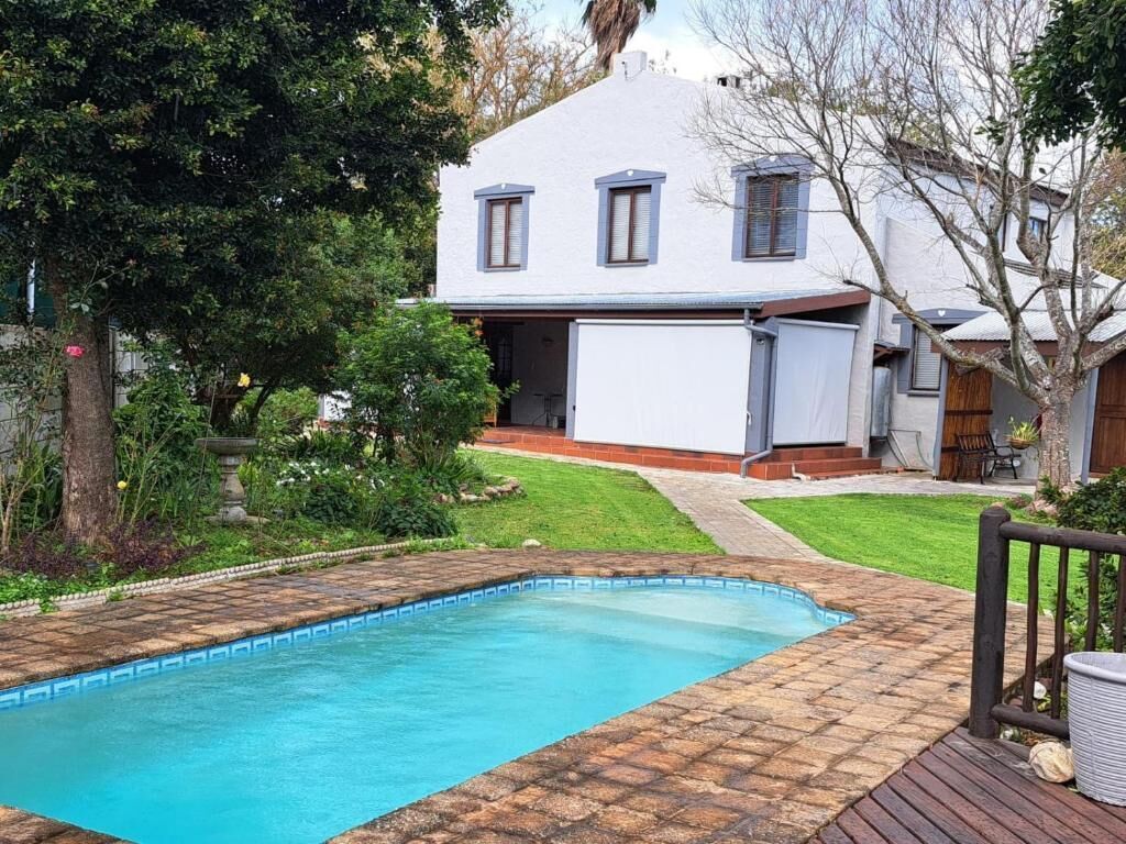 A residential property with a swimming pool, a covered patio, and a house with a sloped roof.