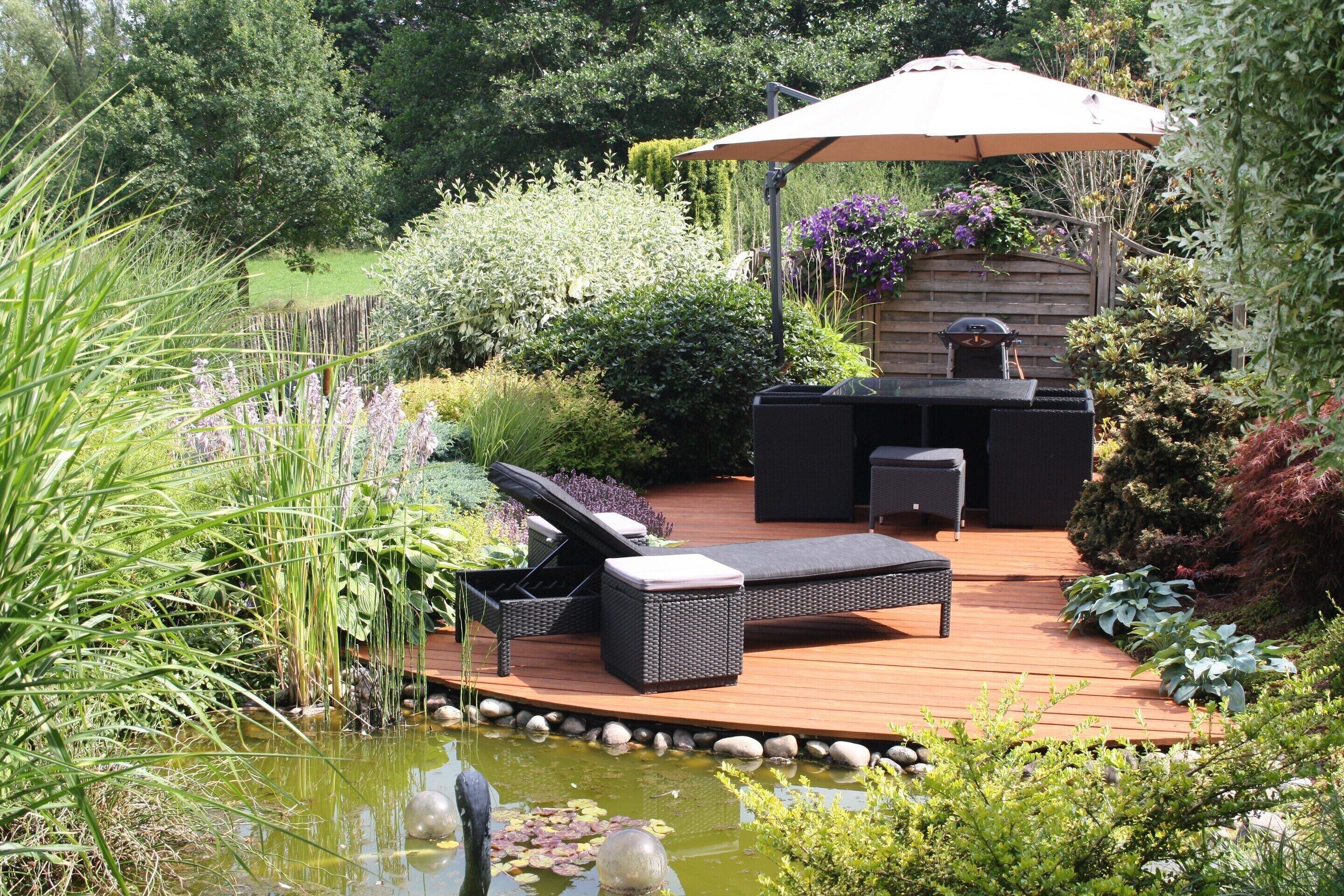 Una terraza con mobiliario exterior, una parrilla y un estanque.