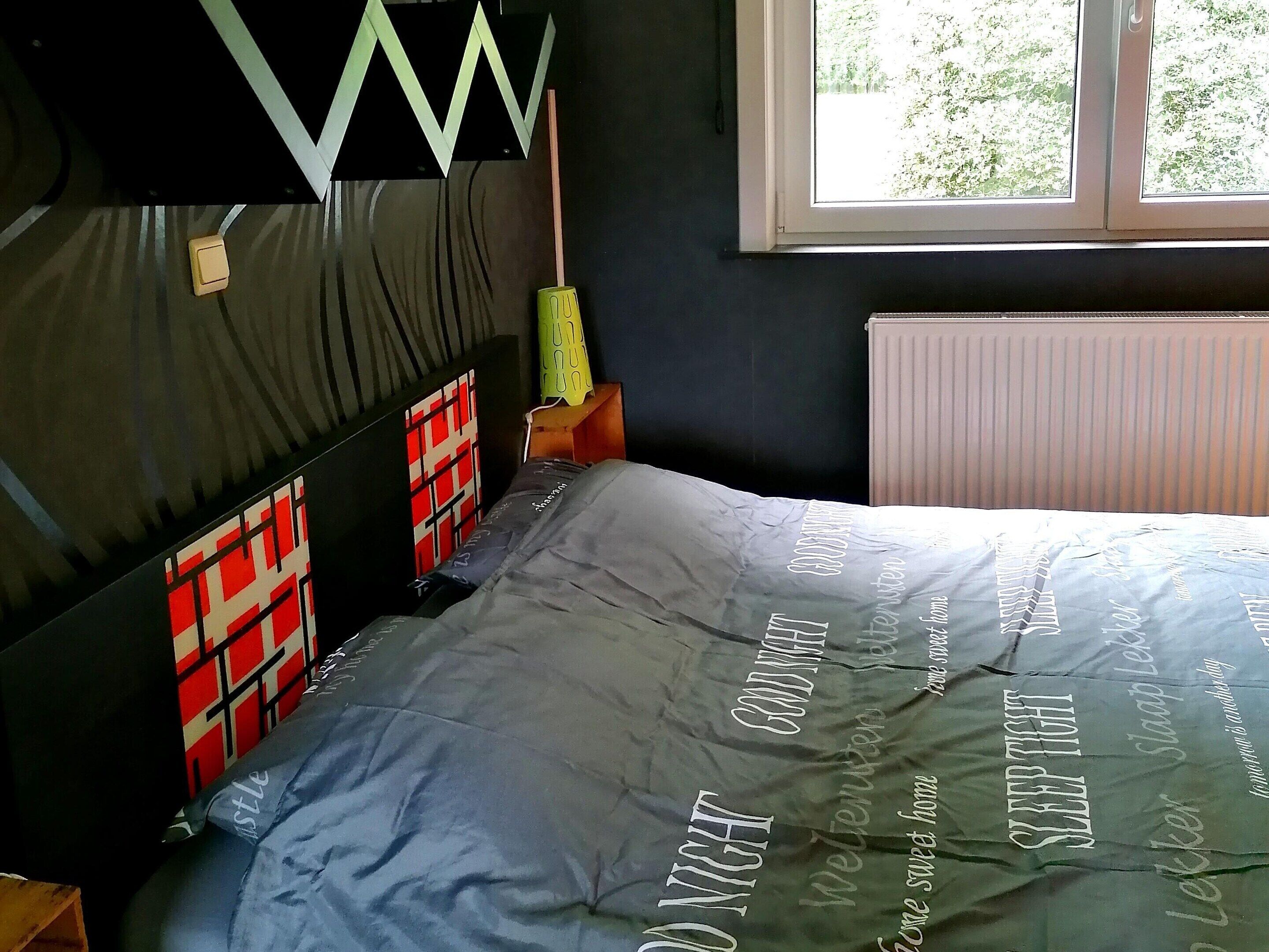 A bedroom with a bed, a window, and a radiator.