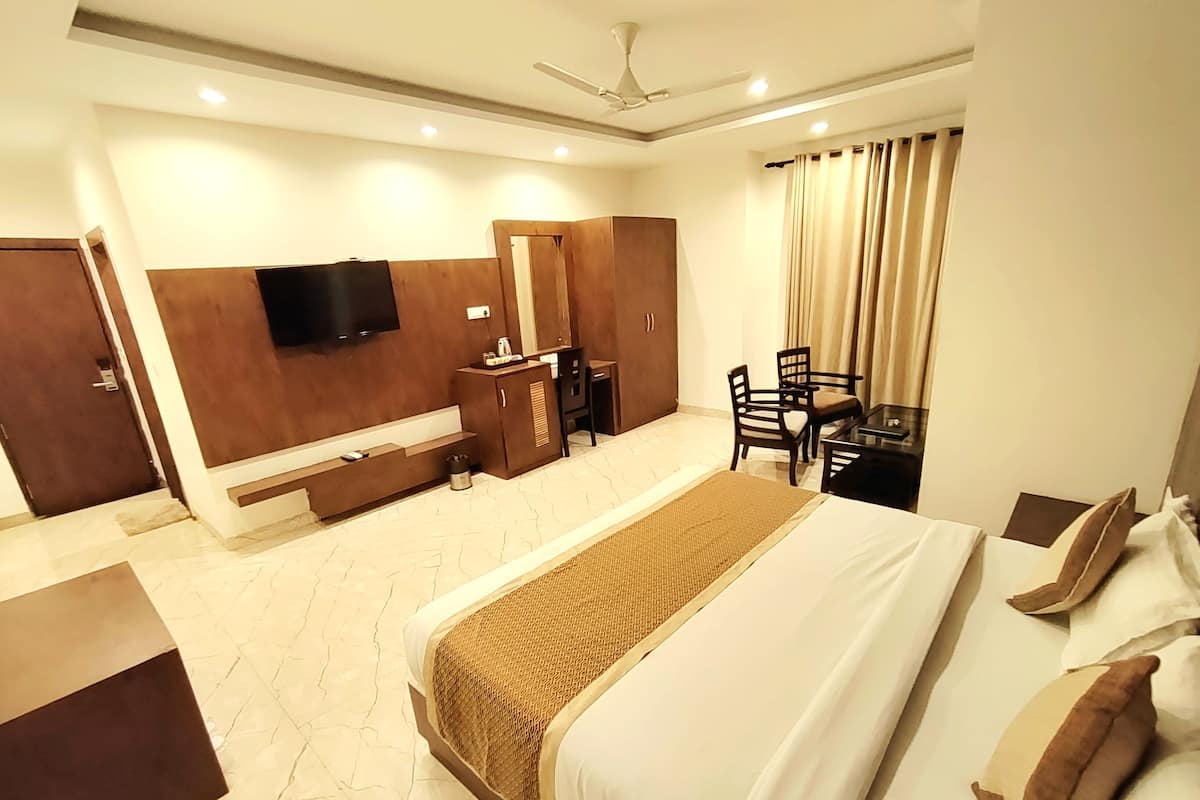 A hotel room with a bed, a desk, a chair, a television, and a wardrobe.