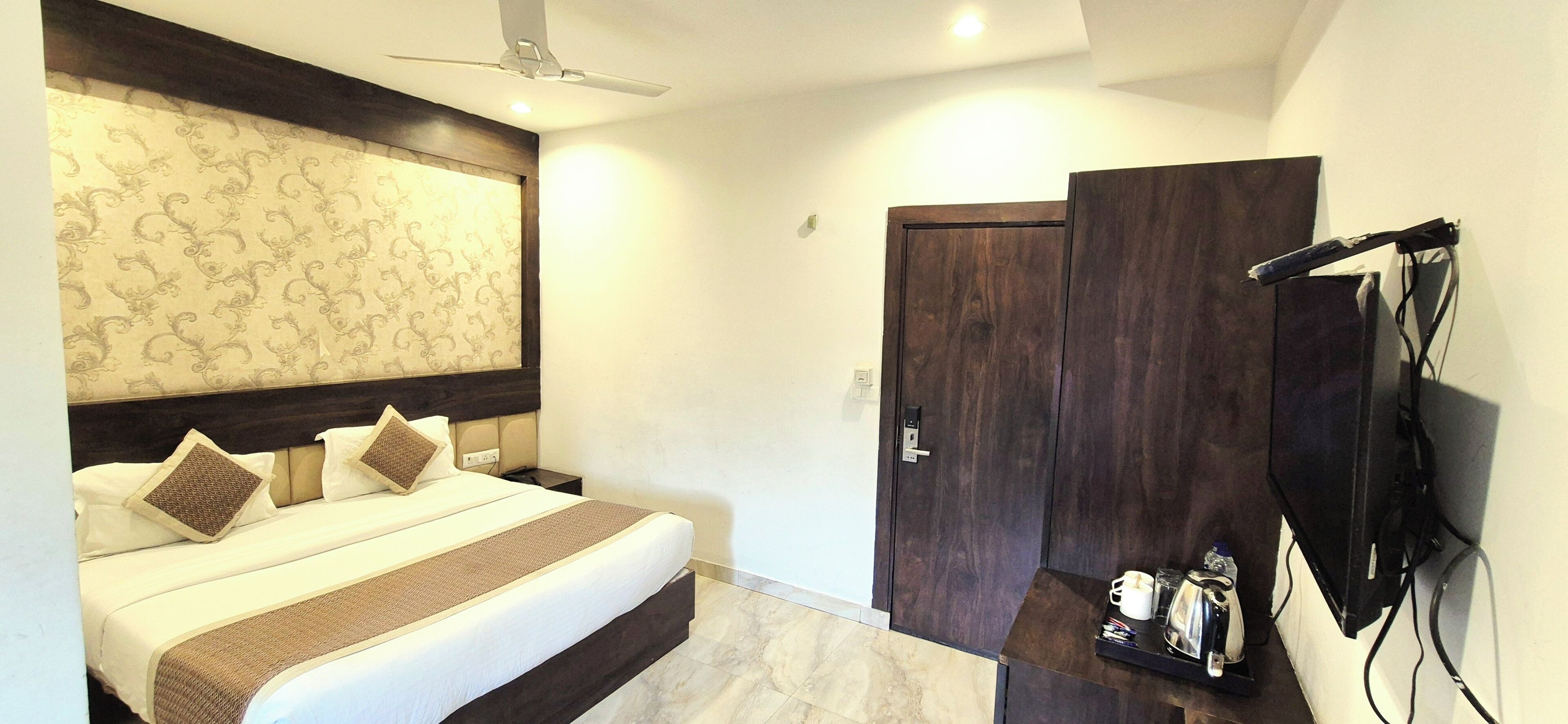Un dormitorio con cama, armario, televisor y ventilador de techo.