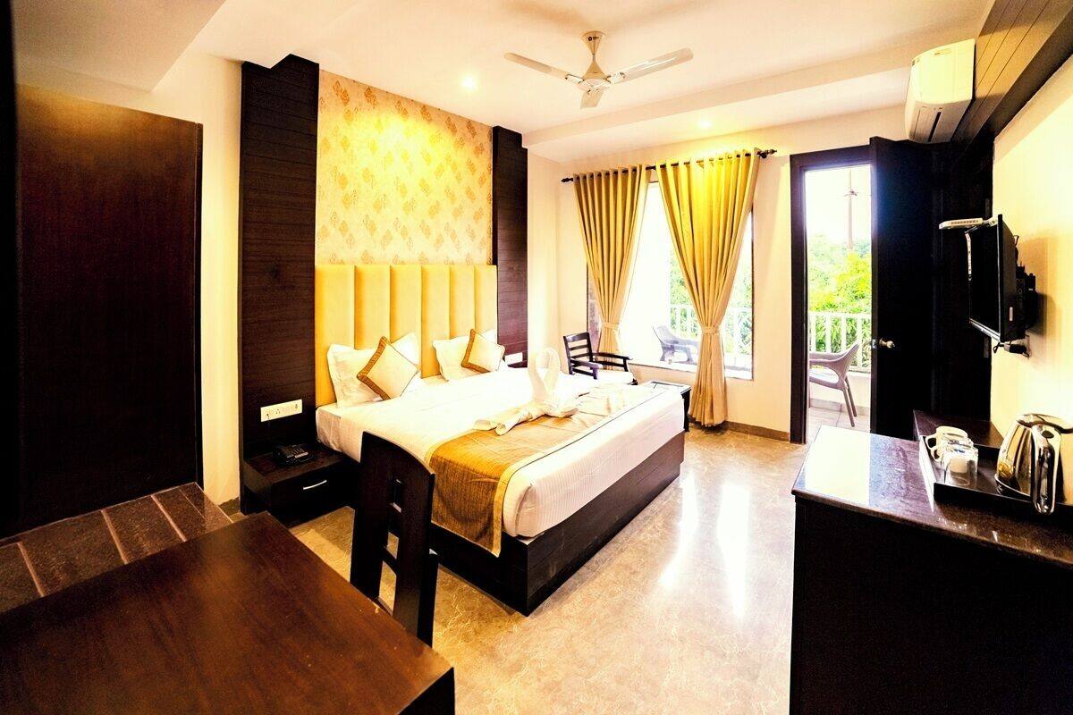 A hotel room with a bed, a desk, a chair, a TV, and a balcony with a view.