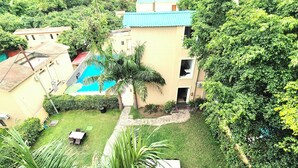 A residential area with a swimming pool, a small garden, and a building with a blue roof. - La Savanna Resort And Spa By DL Hotels And Resorts (Ramnagar)