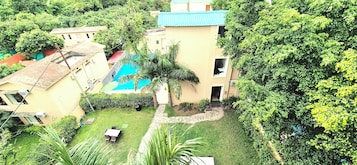 Un barrio residencial con piscina, un pequeño jardín y un edificio de techo azul.