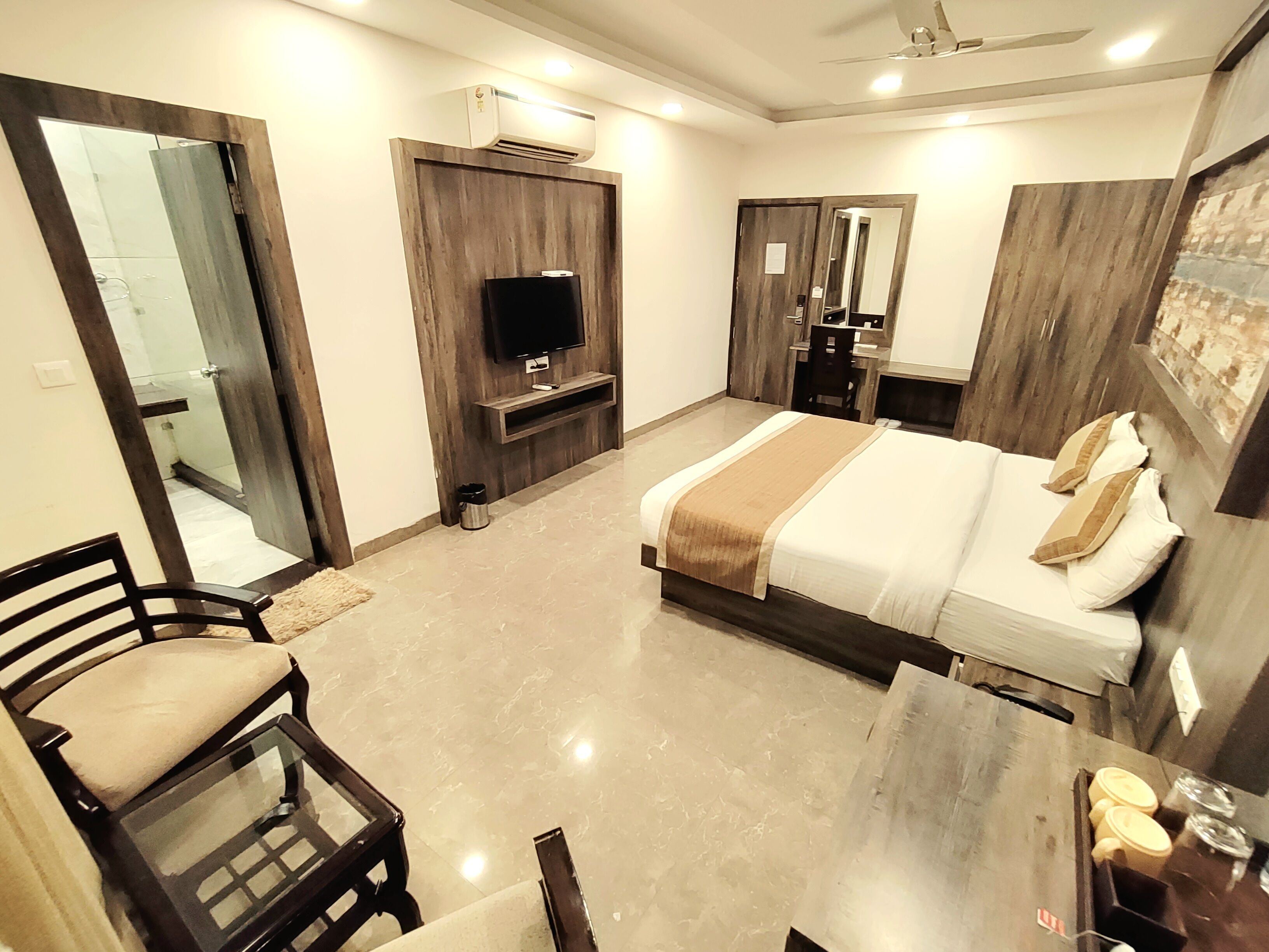 A modern hotel room with a bed, a TV, a desk, and a wardrobe.