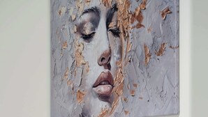 Une chambre à coucher avec un lit, des oreillers et une œuvre d’art accrochée au mur.