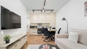 Un salon moderne doté d’un téléviseur à écran plat, d’un canapé, d’une table basse et d’un coin repas avec des chaises et une table.