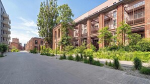 Un bâtiment à la façade en briques, doté de grandes fenêtres et d’un trottoir dallé.