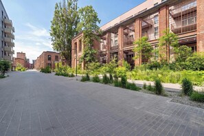 A building with a brick facade, large windows, and a paved walkway. - Charming Apartment with a Terrace | Pets Welcome (Łódź)