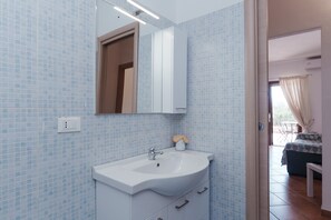 Ein Badezimmer mit einem weißen Waschbecken, einem Spiegel und einer gefliesten Wand.