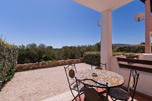 Eine Terrasse mit rundem Tisch und Stühlen, einer Steinmauer und Blick auf die Landschaft.