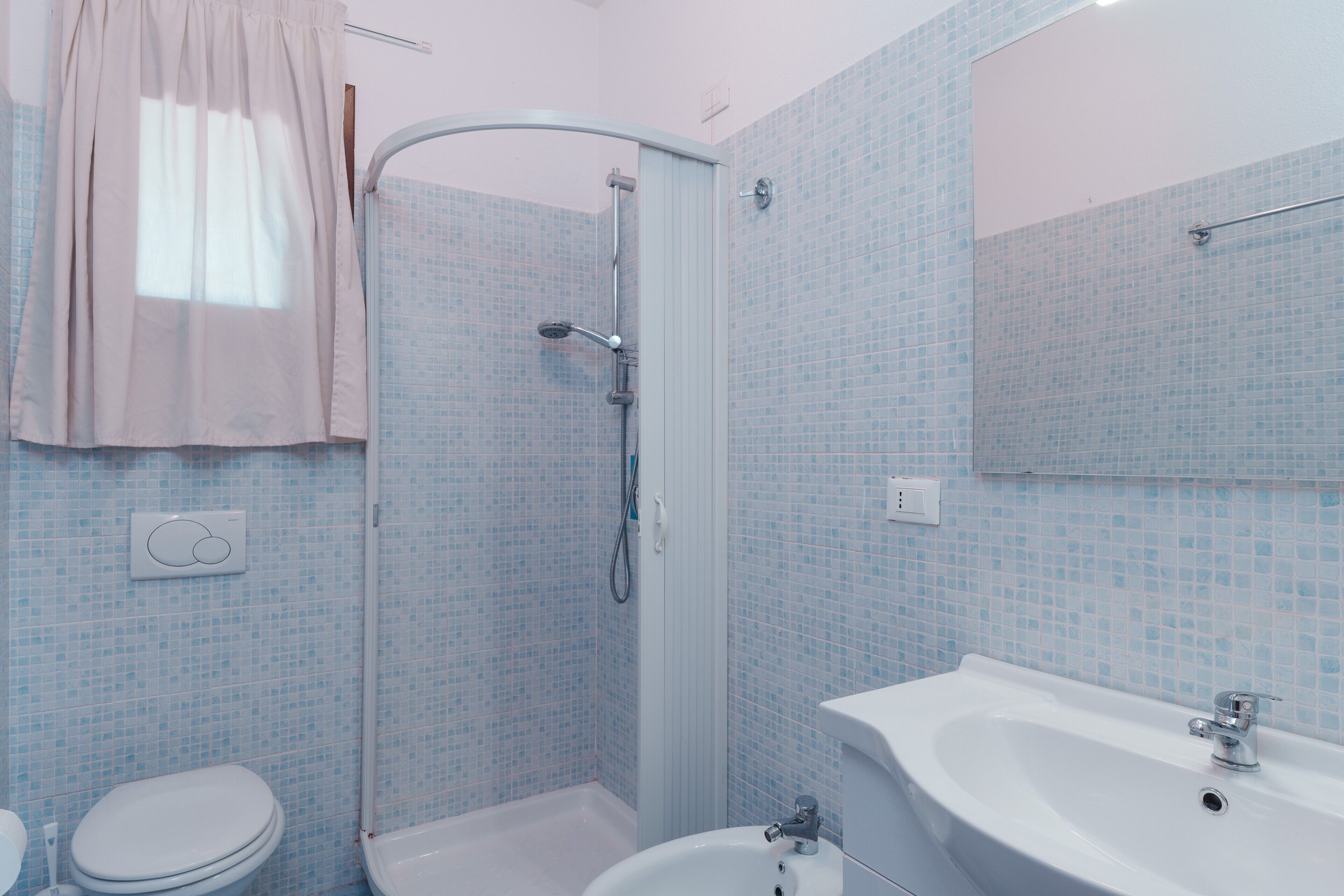 A bathroom with a shower, toilet, sink, and a mirror.