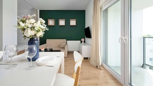Una sala de estar moderna con comedor, sofá, televisor y un amplio ventanal.