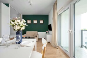 Ein modernes Wohnzimmer mit Essbereich, einer Couch, einem Fernseher und einem großen Fenster.