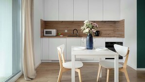Una cocina moderna con gabinetes blancos, una pared decorativa de madera, una mesa de comedor con sillas y un florero con flores.