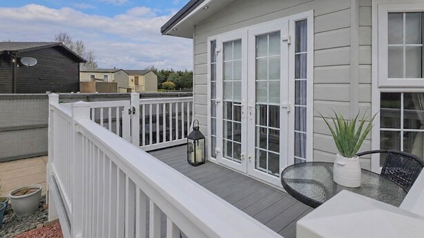 Une terrasse d’habitation avec une table en verre, une plante en pot et une lanterne.
