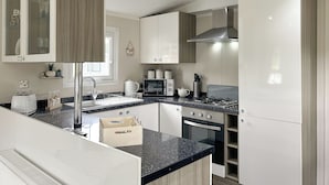 Une cuisine moderne avec des meubles blancs, une cuisinière en acier inoxydable et un four encastré.