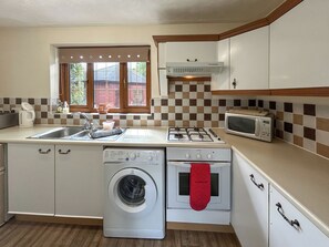 Una cocina compacta equipada con lavadora, microondas, cocina y pileta.