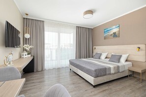 Ein modernes Hotelzimmer mit einem großen Bett, einem Schreibtisch und Blick auf die Stadt.