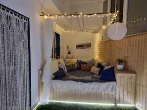 Een gezellige kamer met een bed, lichtslingers, een witte lantaarn en een plant.