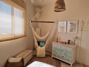 Een kamer met een hangmat, een houten kist, een dressoir en kunst aan de muur.