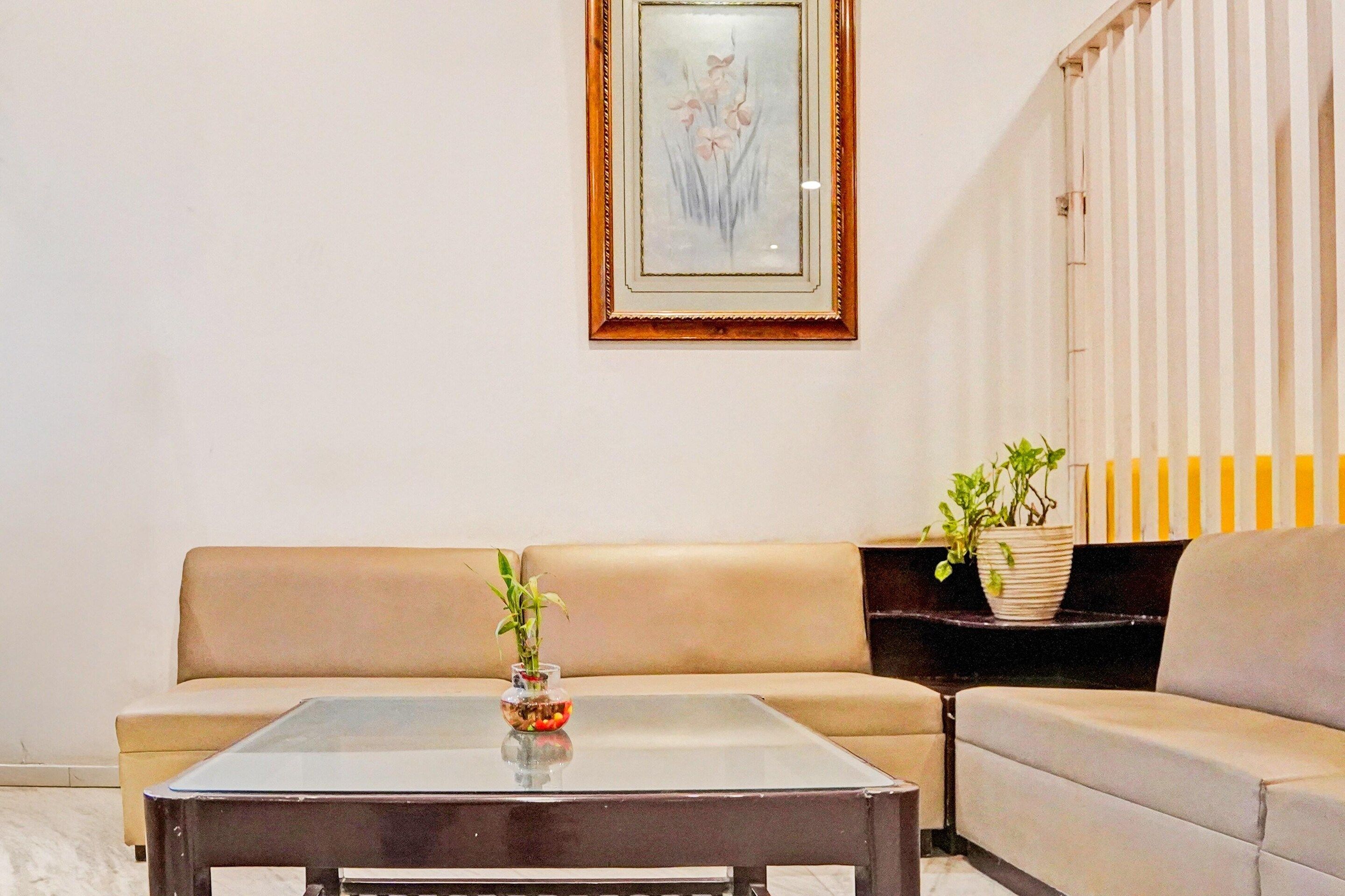 A living room with a sofa, a coffee table, and two potted plants.